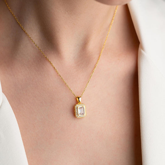 Baguette-cut pendant necklace with cubic zirconia stones, available in 925 sterling silver and 14K gold plated options, displayed on a white satin background