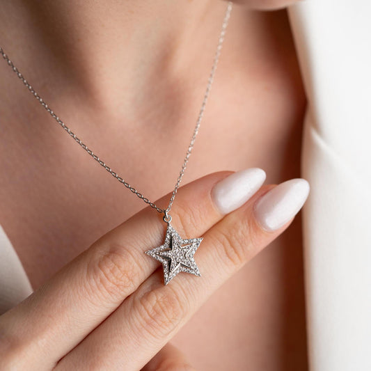 Star pendant necklace with cubic zirconia stones, available in 925 sterling silver and 14K gold plated options, displayed on a white satin background.