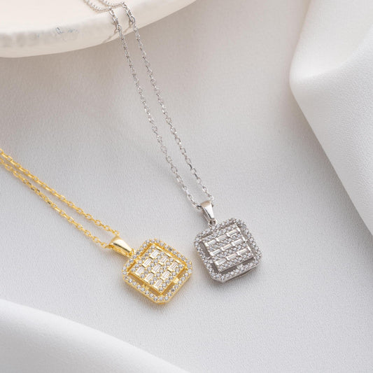 Square baguette pendant necklace with cubic zirconia stones, available in 925 sterling silver and 14K gold plated options, displayed on a white satin background