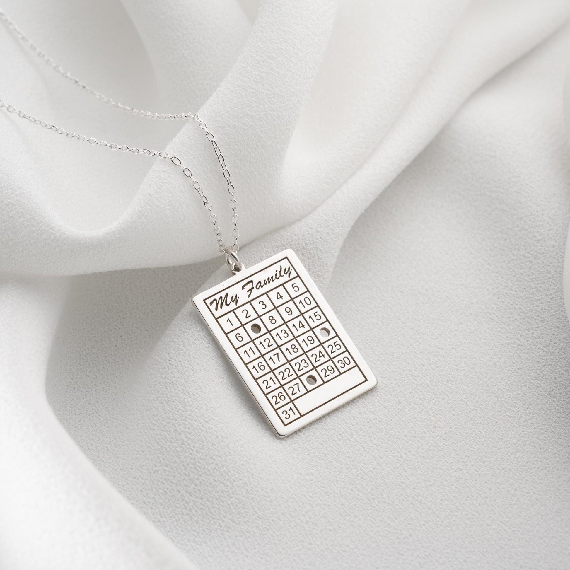 A personalized calendar necklace with a custom date engraving, available in sterling silver and gold plated finishes. The perfect anniversary, birthday, or wedding gift for her.