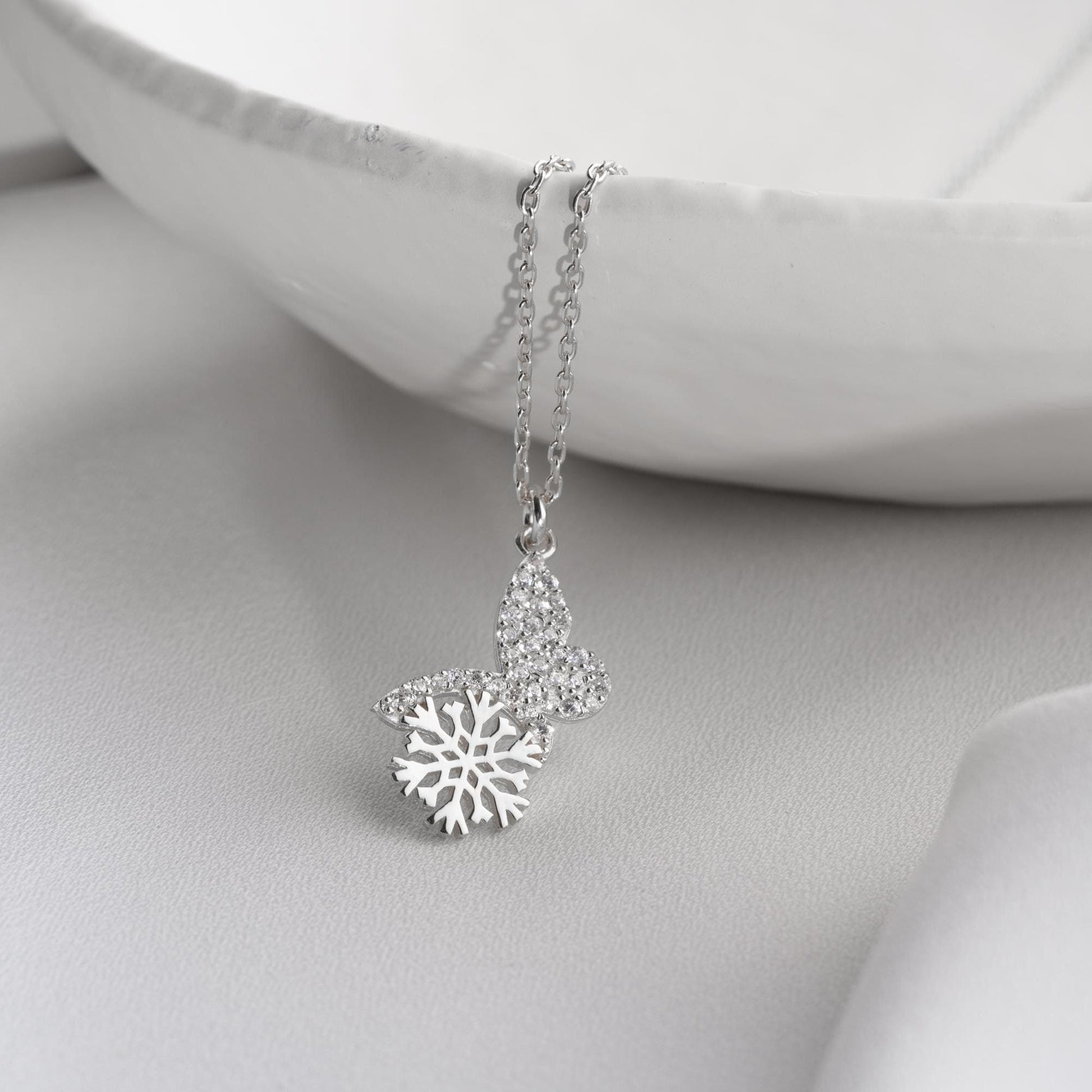 Snowflake heart necklace with cubic zirconia stones, available in 925 sterling silver and 14K gold plated options, displayed on a white satin background