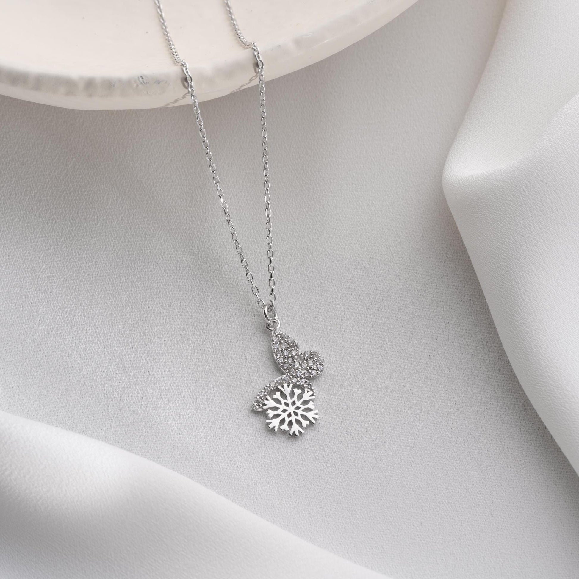 Snowflake heart necklace with cubic zirconia stones, available in 925 sterling silver and 14K gold plated options, displayed on a white satin background