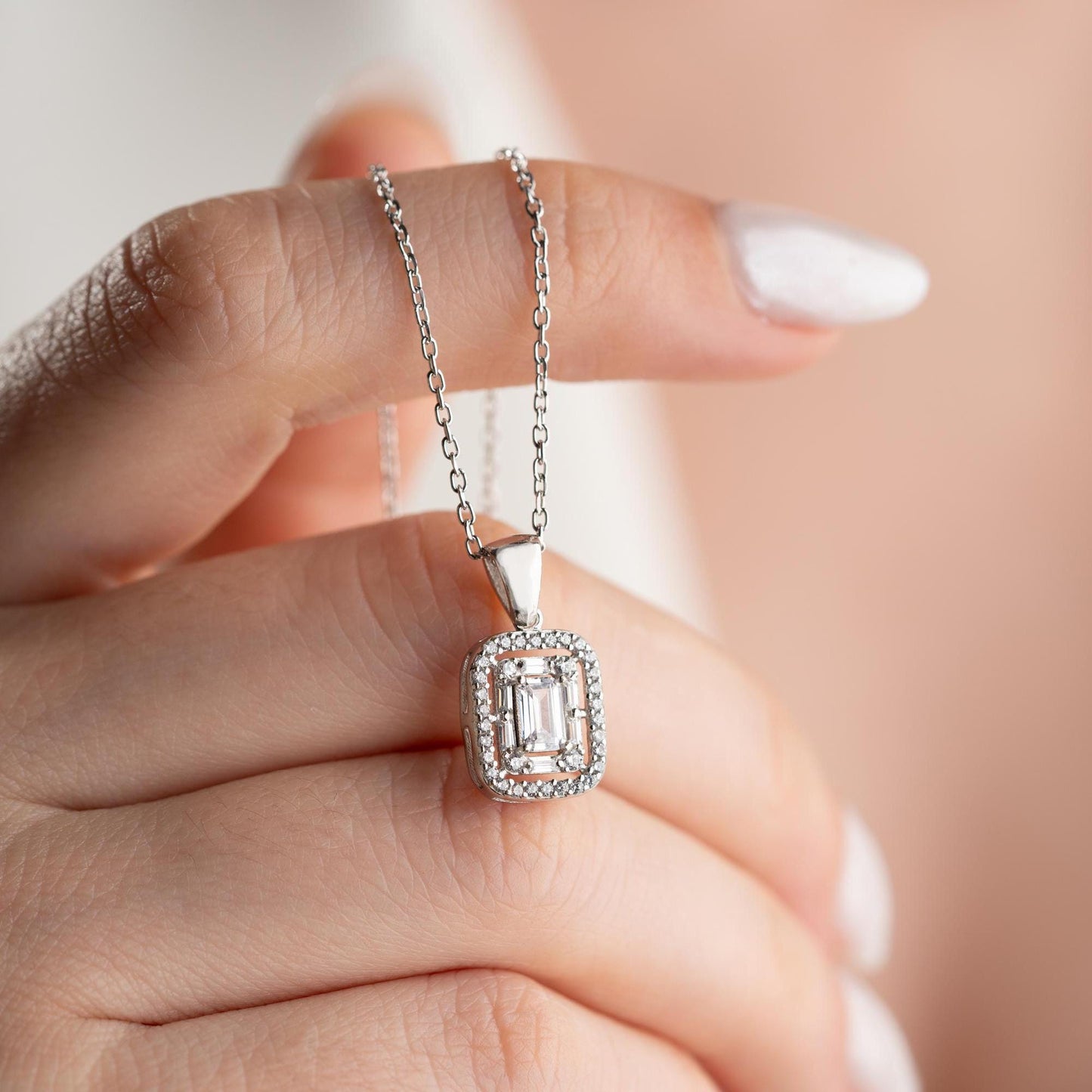 Square baguette pendant necklace with cubic zirconia stones, available in 925 sterling silver and 14K gold plated options, displayed on a white satin background.