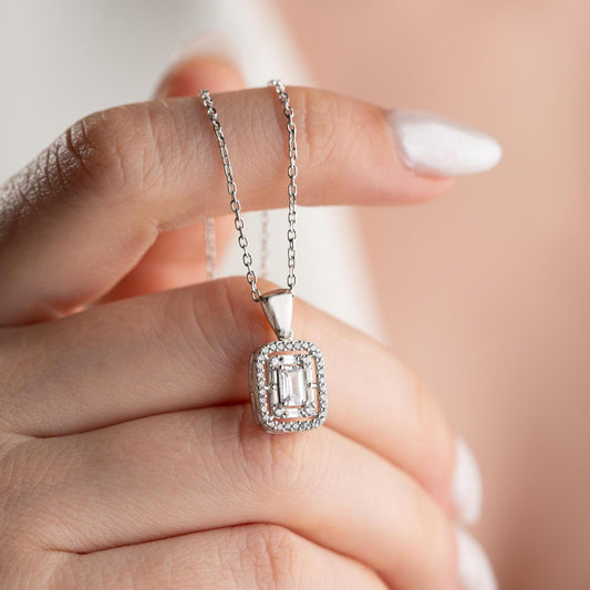 Square baguette pendant necklace with cubic zirconia stones, available in 925 sterling silver and 14K gold plated options, displayed on a white satin background.