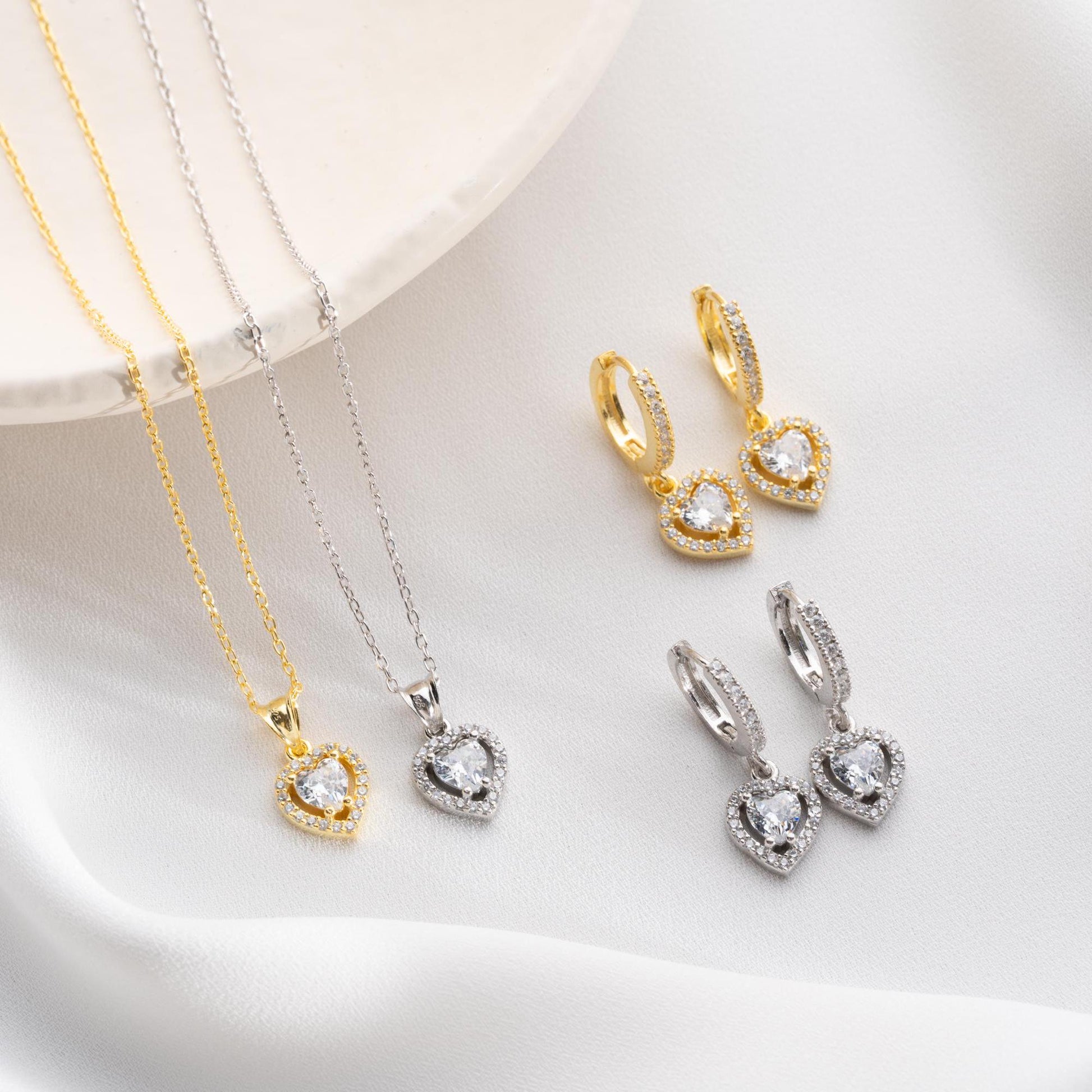 Heart pendant necklace and earrings set, crafted in 925 sterling silver with cubic zirconia stones, displayed on a soft satin background