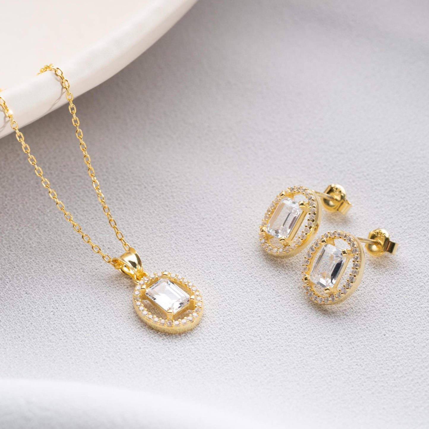 Oval elegance jewelry set with pendant necklace and earrings, featuring cubic zirconia stones, available in 925 sterling silver and 14K gold-plated options.