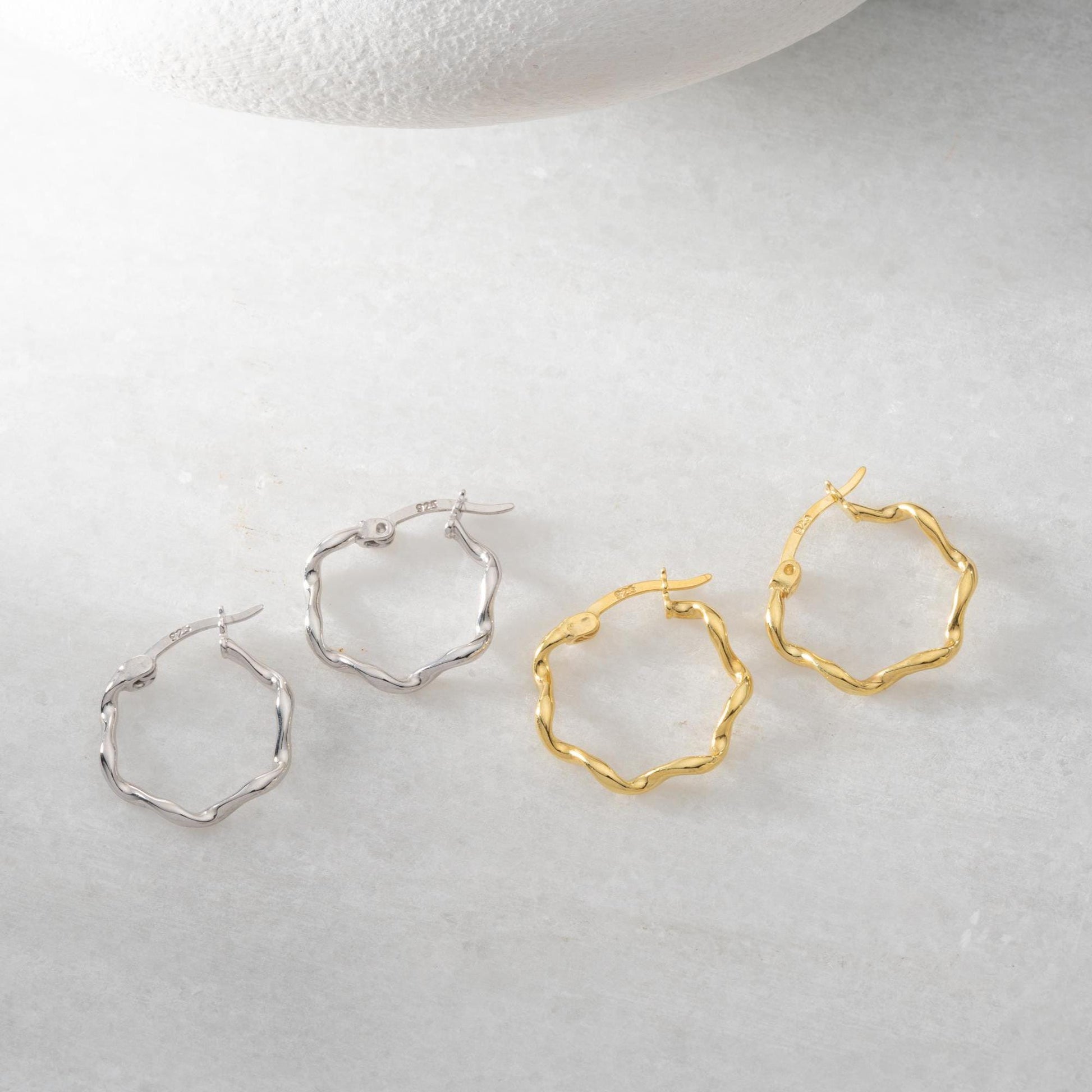 Wave hoop earrings crafted from 925 sterling silver with 14K gold plating option, displayed on a marble background.