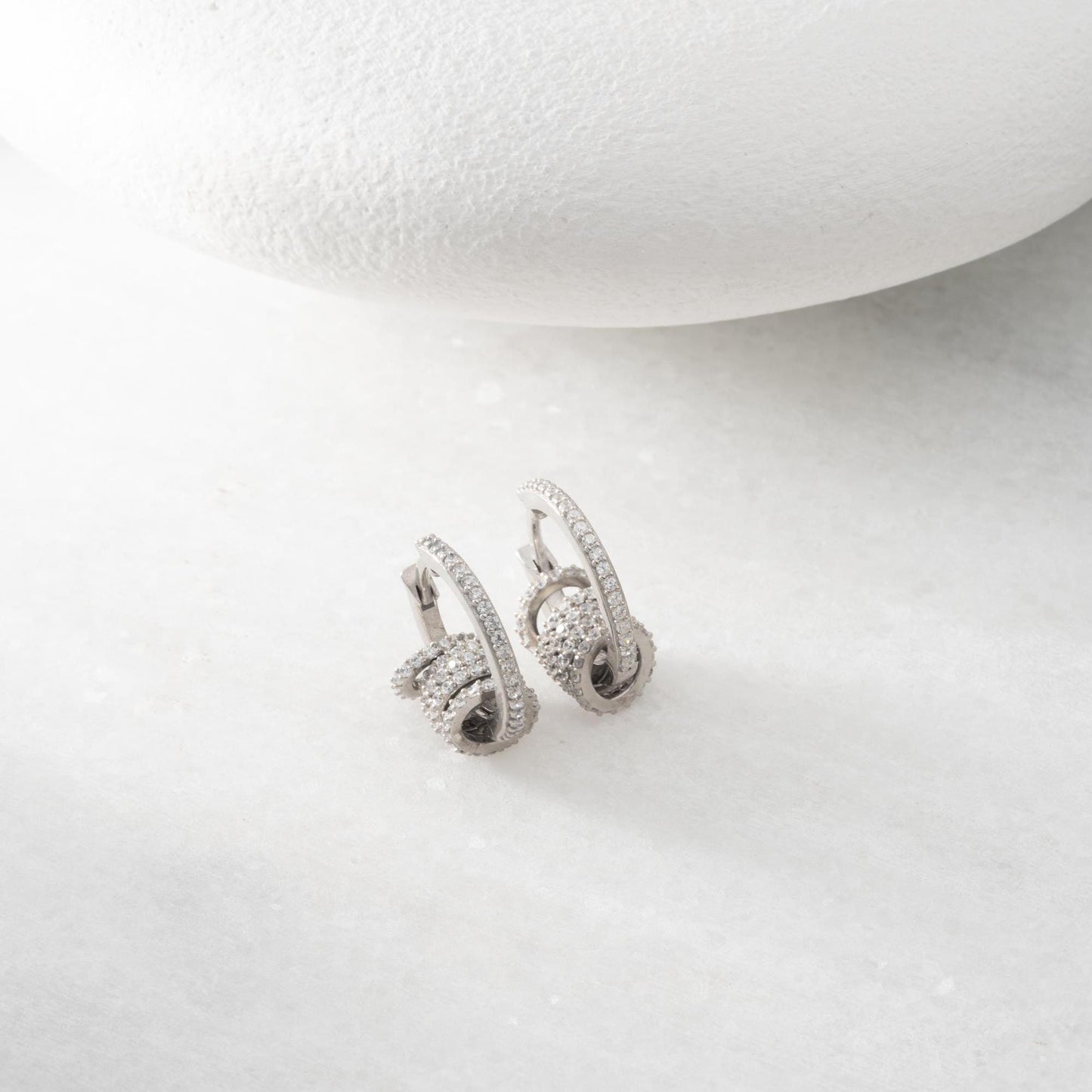 Multi-ring hoop earrings with sparkling cubic zirconia stones in 925 sterling silver and 14K gold-plated options, displayed on a marble background.