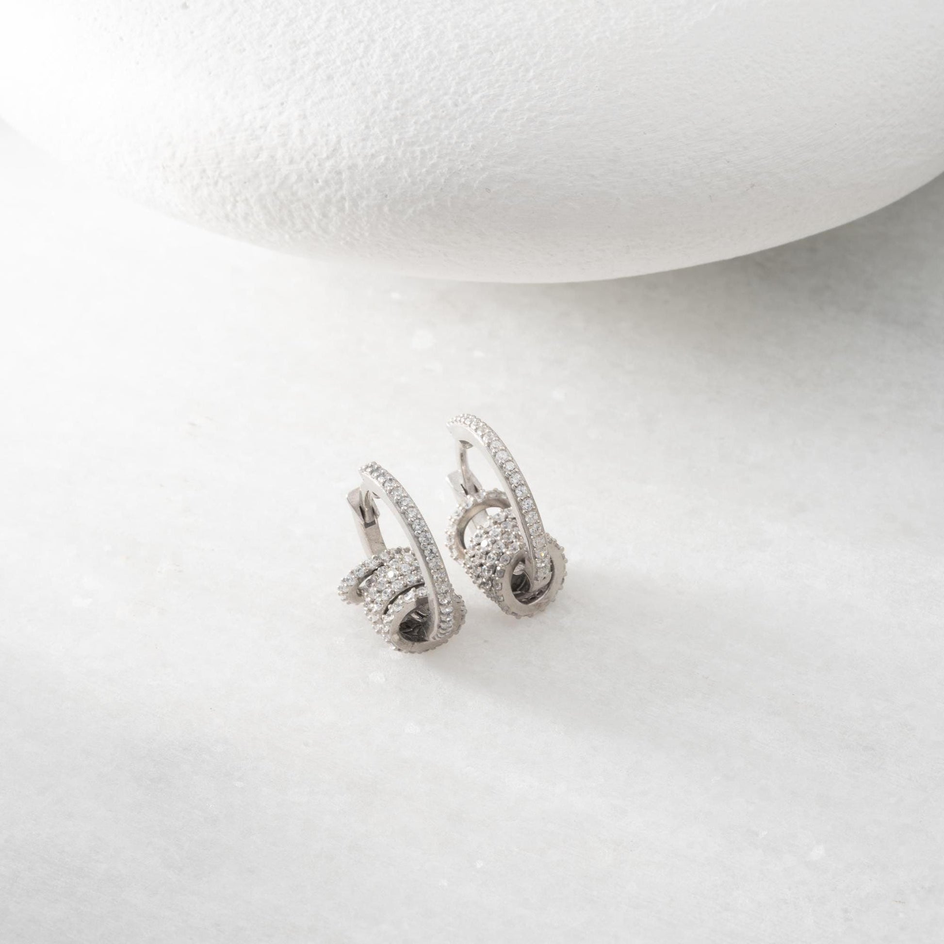 Multi-ring hoop earrings with sparkling cubic zirconia stones in 925 sterling silver and 14K gold-plated options, displayed on a marble background.