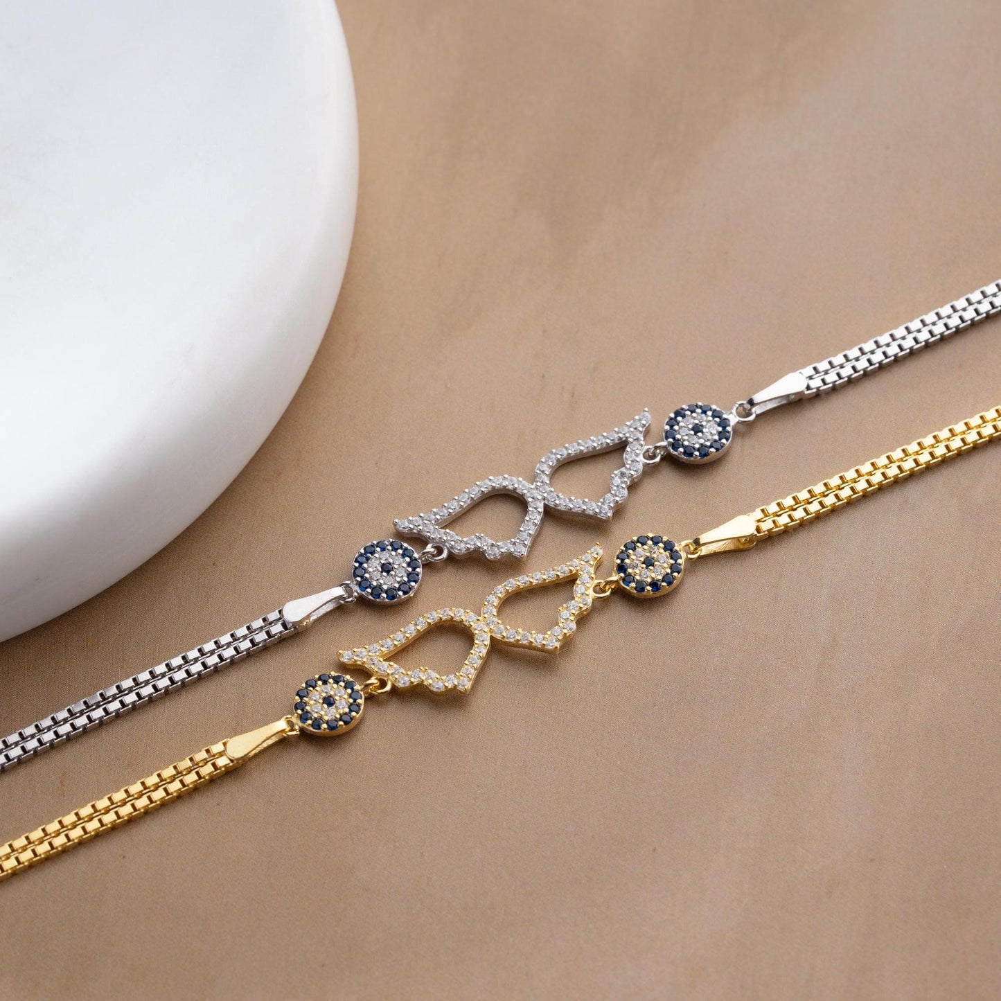 A luxurious Turkish-inspired evil eye and angel wing charm bracelet crafted in 925 sterling silver with sparkling cubic zirconia stones, available in gold and silver options.