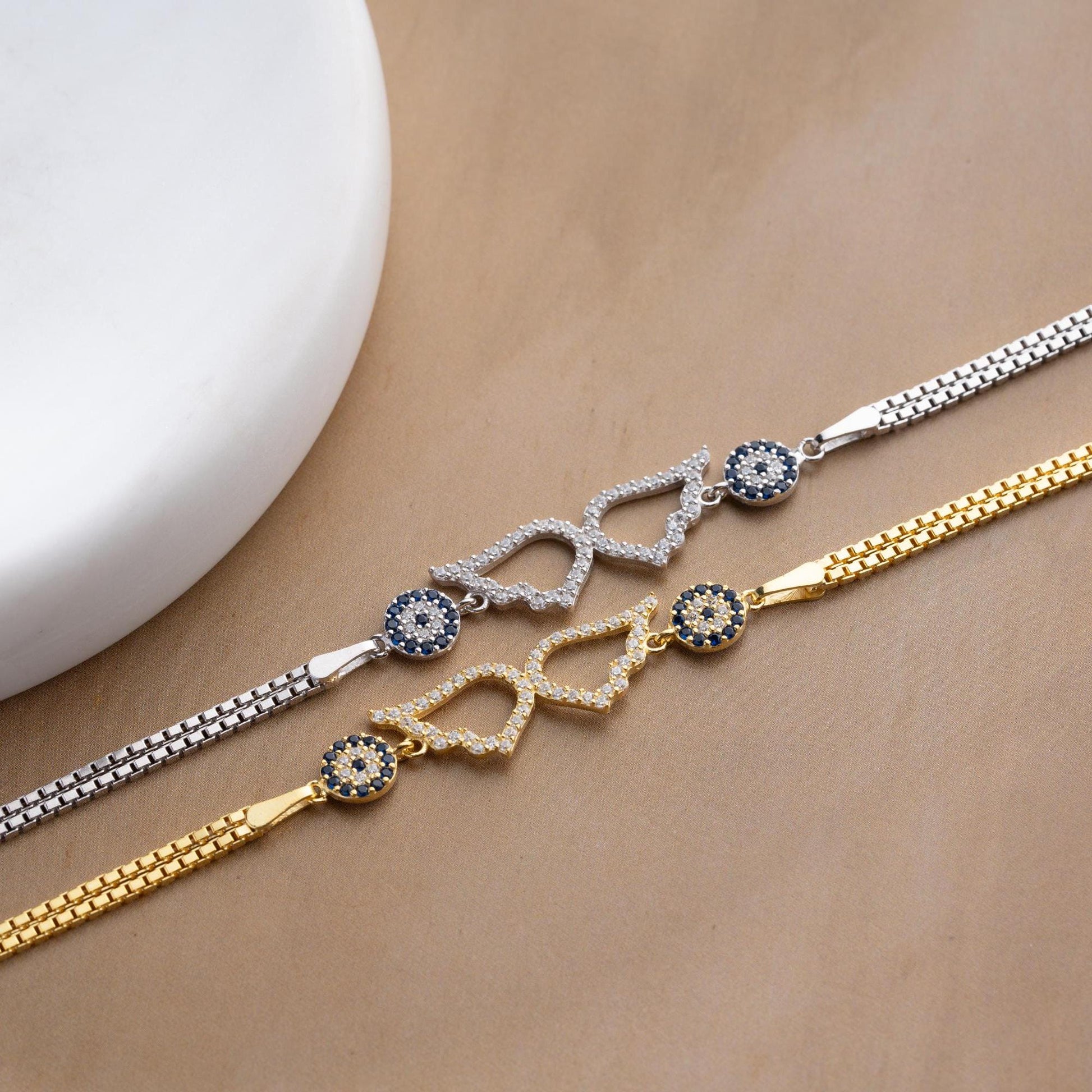 A luxurious Turkish-inspired evil eye and angel wing charm bracelet crafted in 925 sterling silver with sparkling cubic zirconia stones, available in gold and silver options.