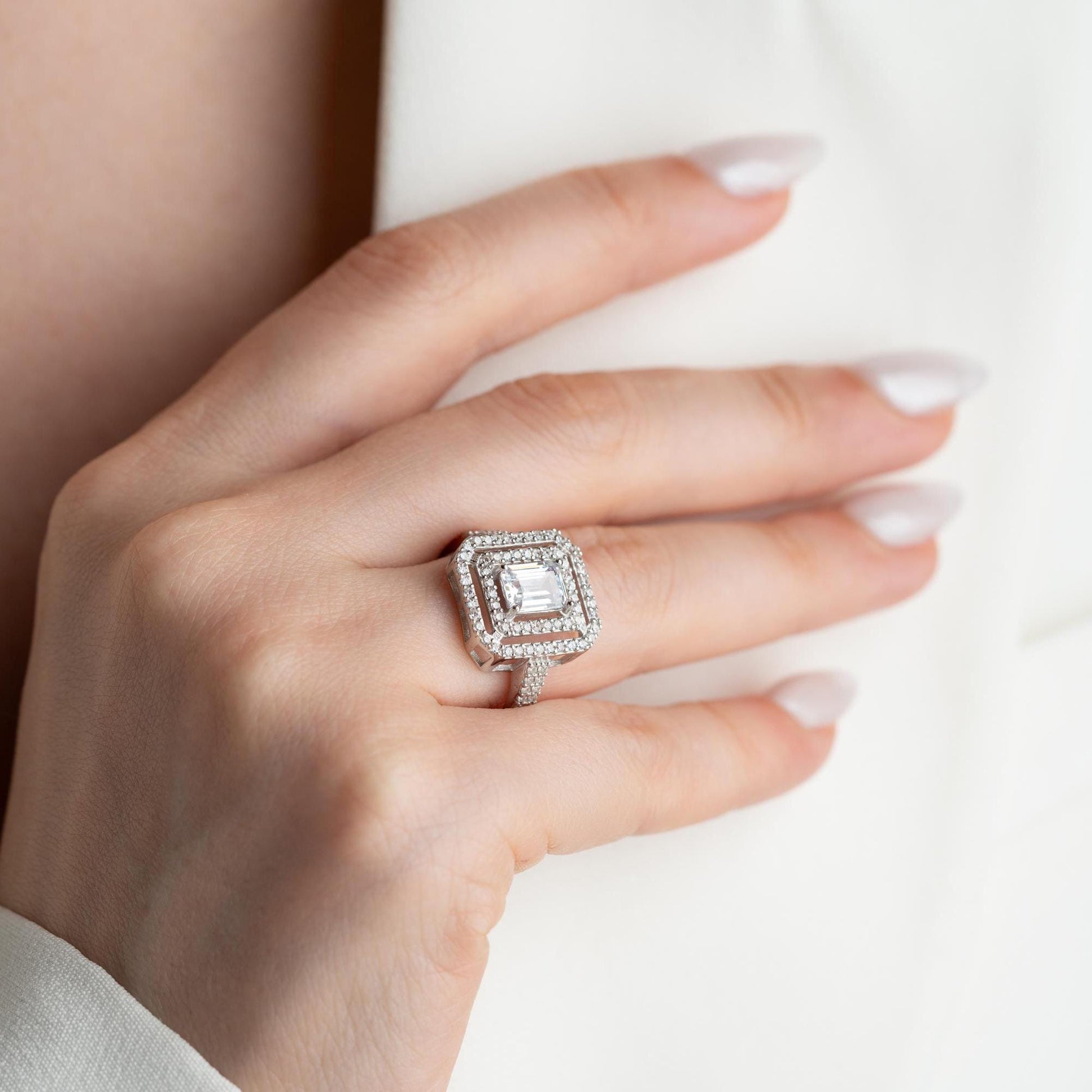 Elegant emerald cut double halo statement ring crafted in 925 sterling silver with cubic zirconia stones, available in silver and gold plated finishes.