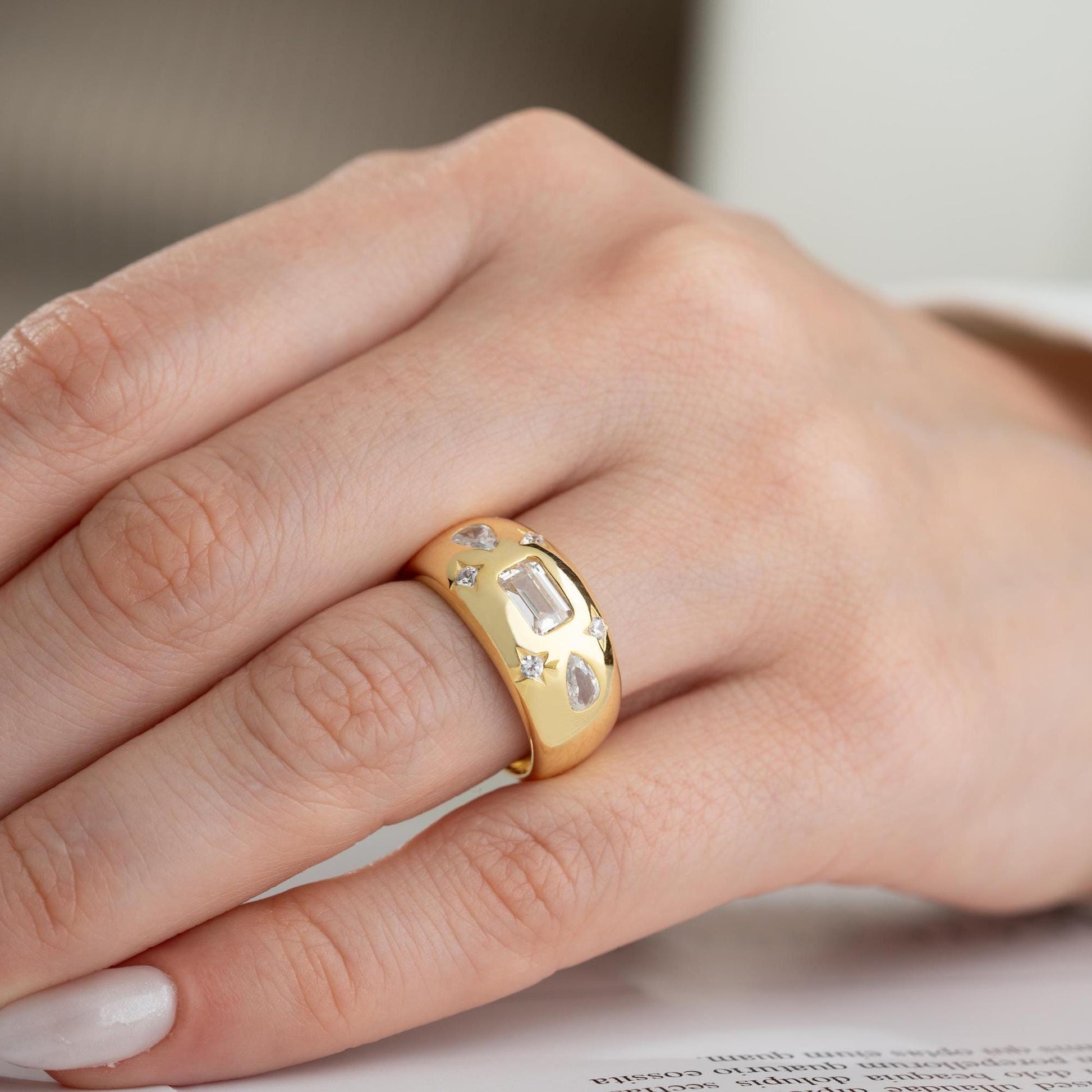 Baguette and teardrop cubic zirconia band ring in 925 sterling silver and 14K gold plating, featuring celestial star motifs. Elegant statement ring for women.