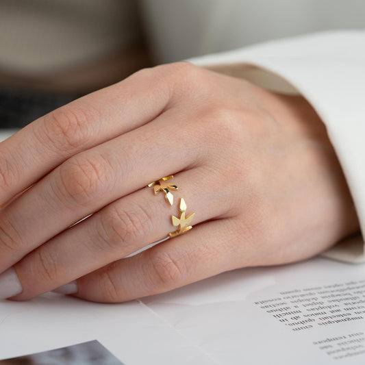 A delicate olive branch-inspired ring crafted from 925 Sterling Silver, available in gold and rose gold plating. Adjustable open band, perfect for nature lovers and elegant gifting.